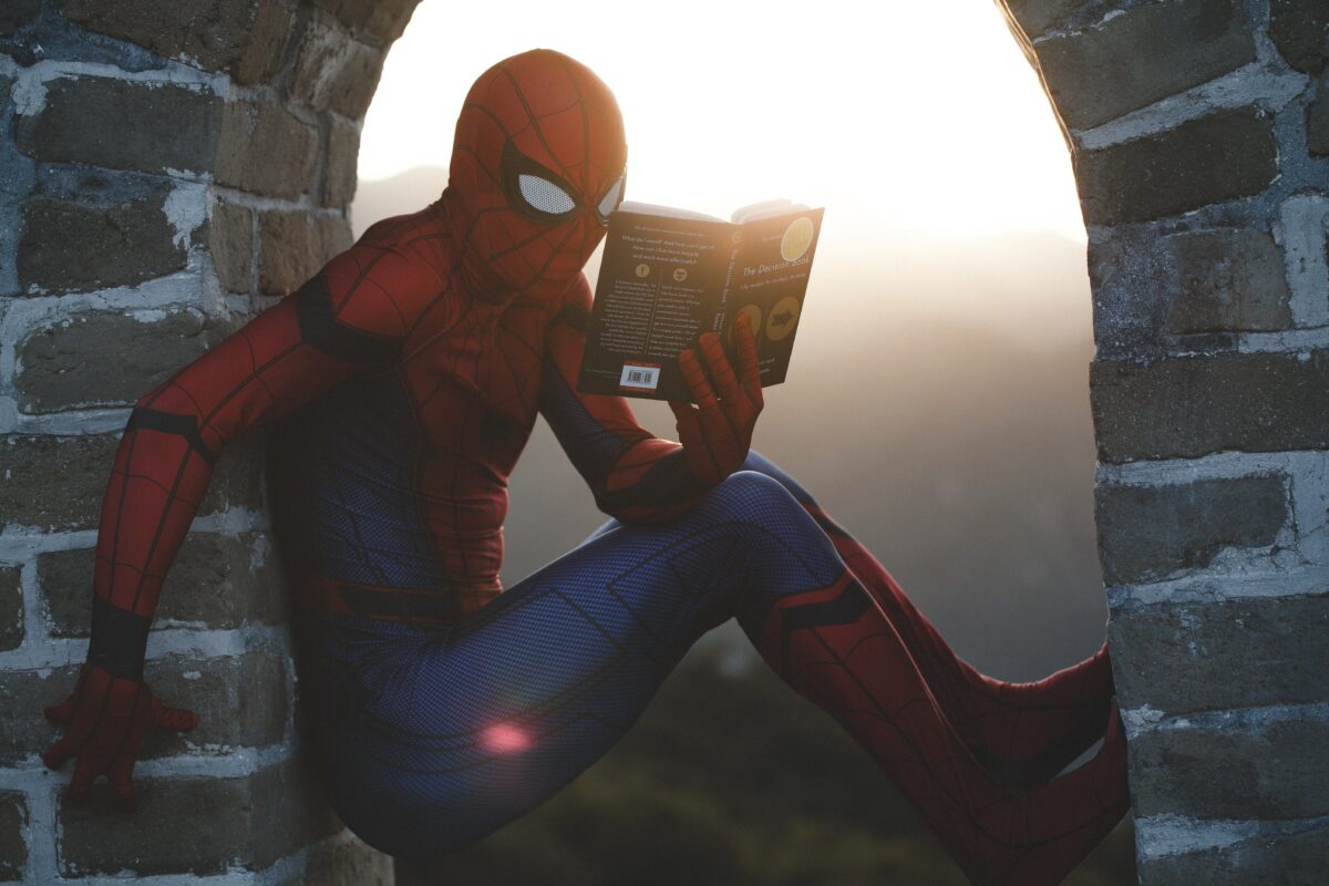 Spider-Man perched in a brick arch, reading a book